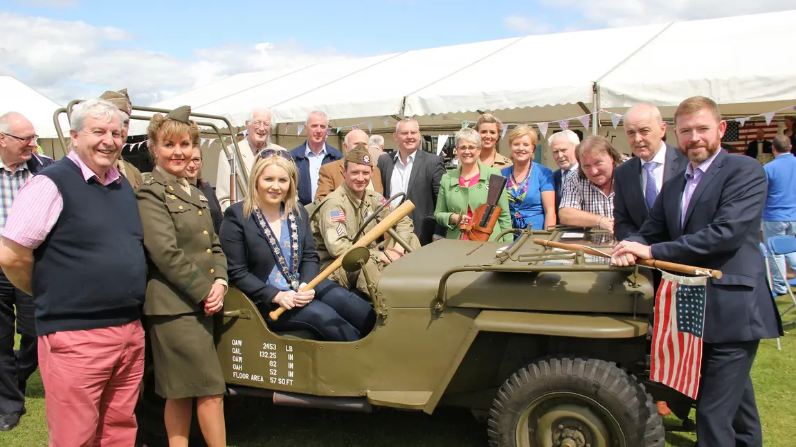 People stand near a military jeep