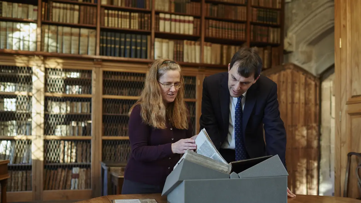 Cathedral Archivist Emily Naish and John Glen MP examine a book from the collection