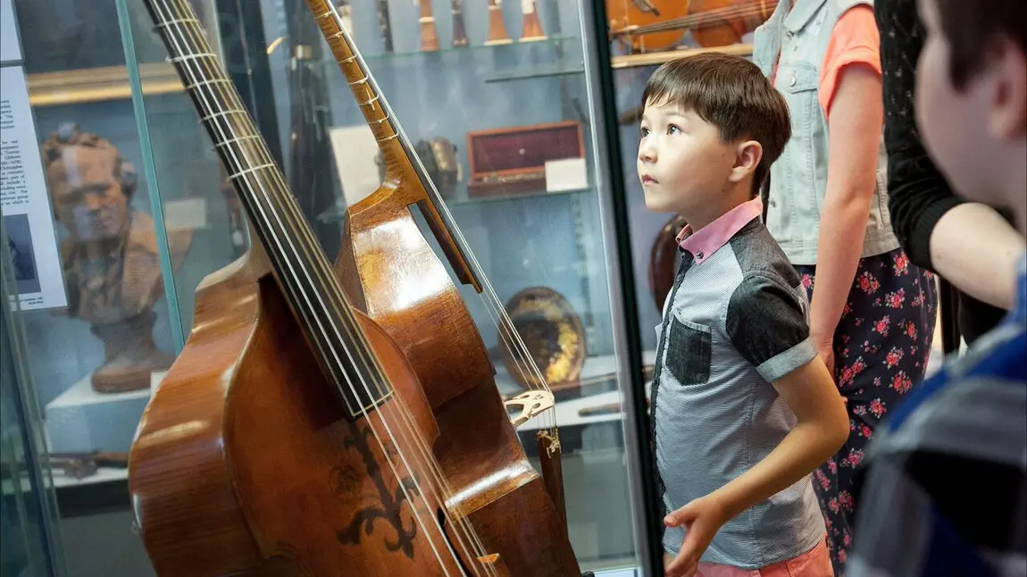 Child looking at a display of instruments in the Royal College of Music Museum Royal College of Music Museum: child looking at instruments
