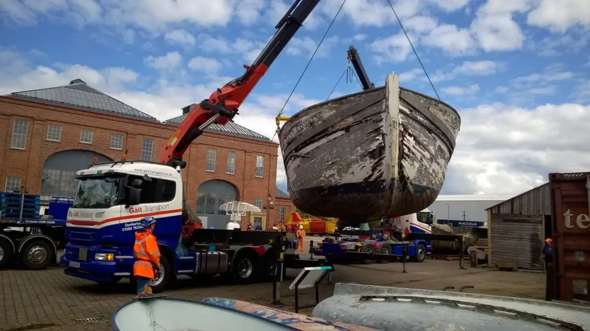 A crane moves a wooden boat