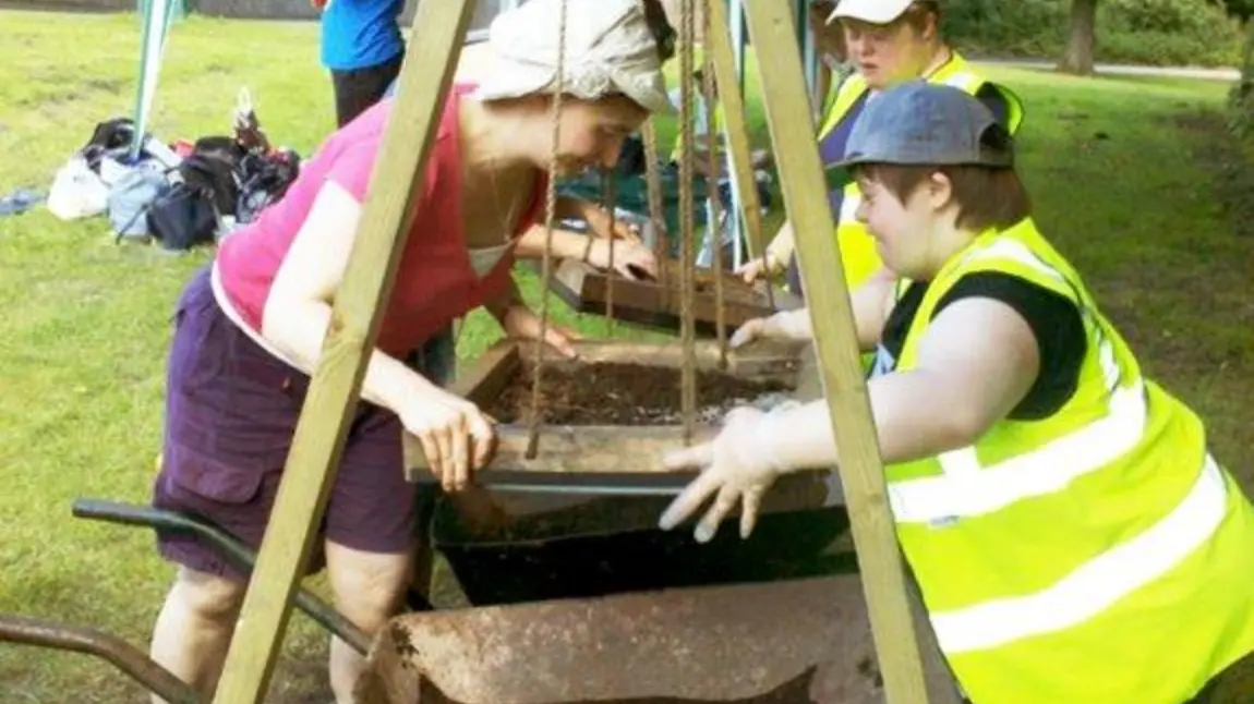 Participants use swing sieves at a community excavation project