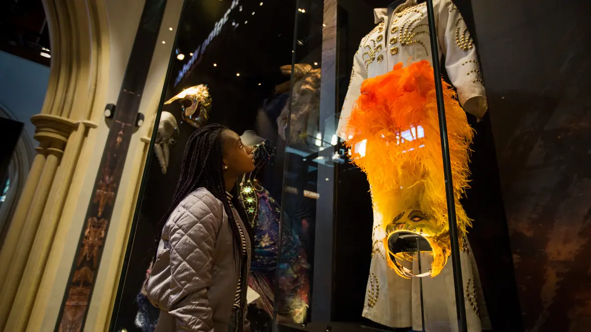 A girl looking at some clothing at The Play’s The Thing exhibition