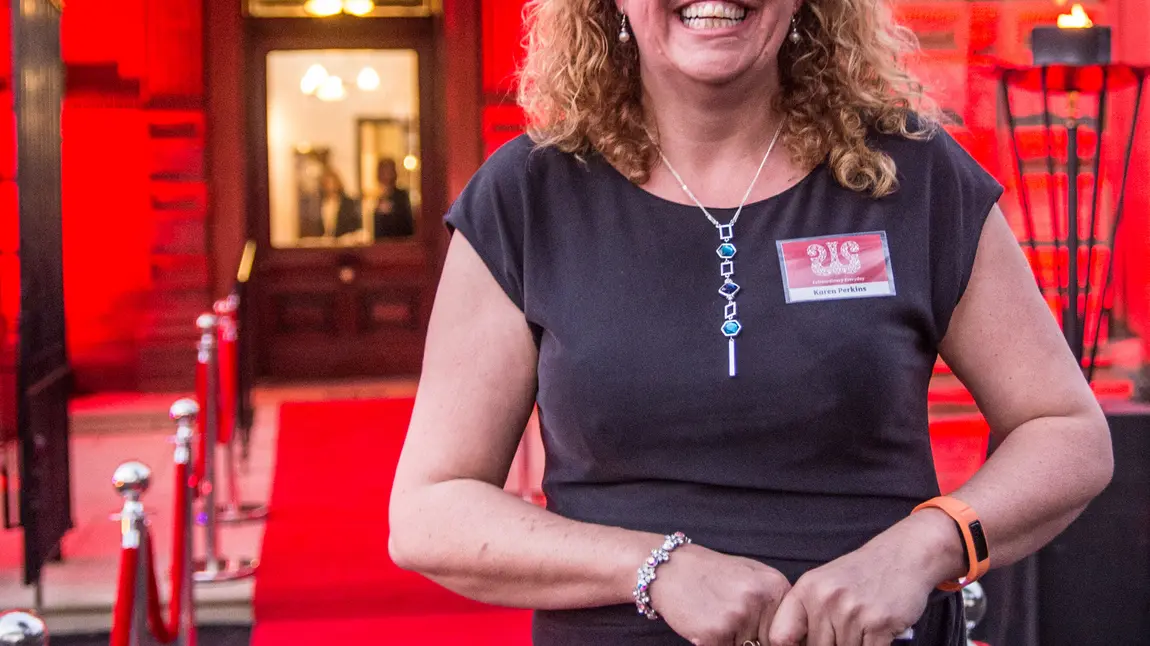 Karen Perkins stands at a red carpet event, smiling broadly