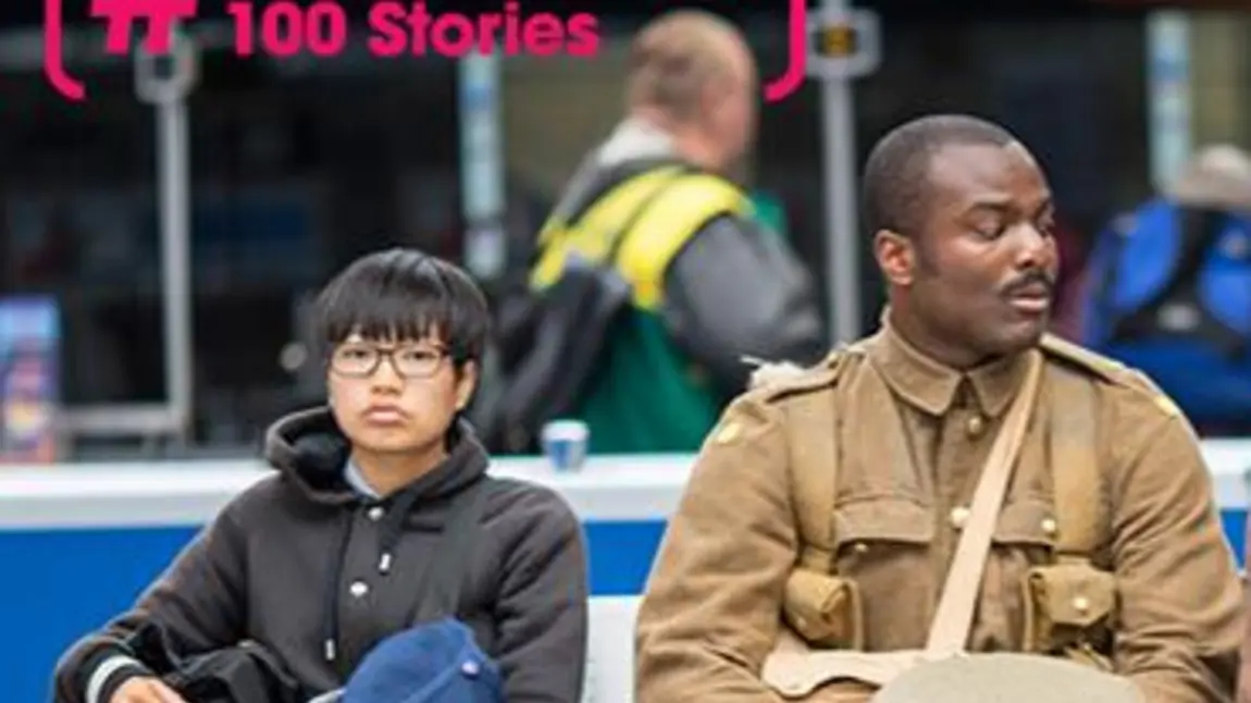 21st century man dressed as First World War soldier sitting next to commuters in a train station  