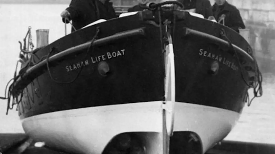 Five men stand in a life boat ready to be launched
