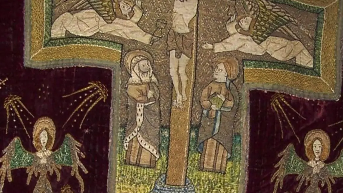 An image of a medival vestment showing a crucifix, religious figures and angles.