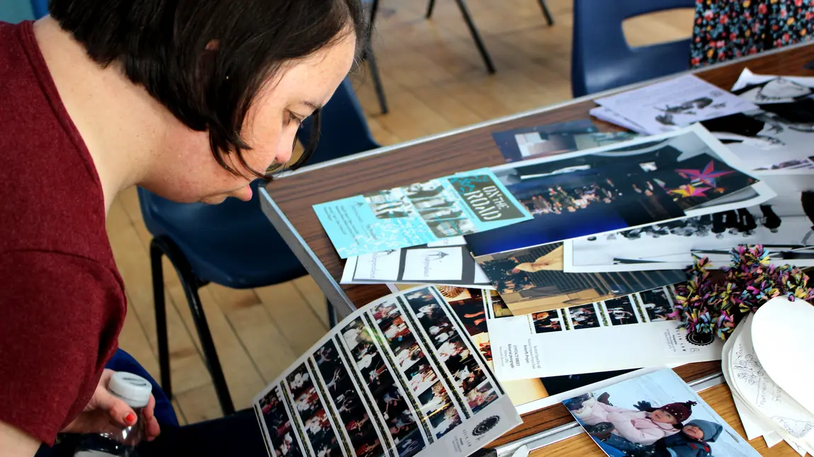 A person at a table looking at photographs and other archive material