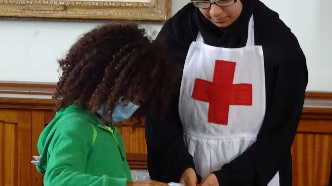 A young participant demonstrates wartime medical techniques to a young visitor