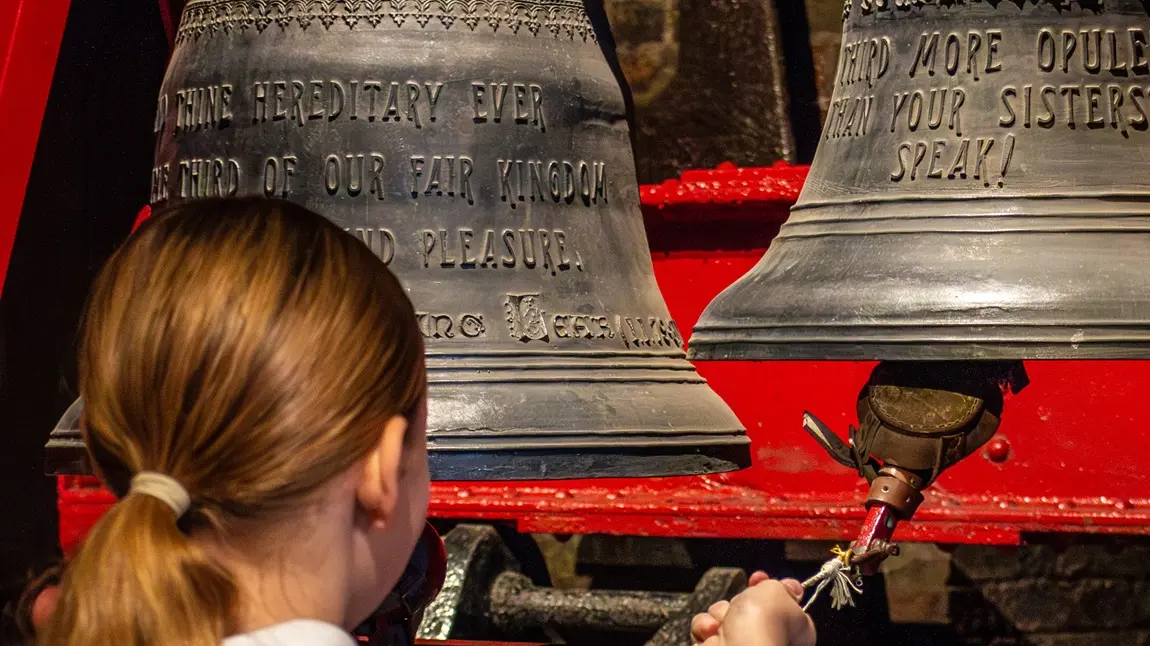 taylors_hero_1.jpg A visiting schoolgirl rings a cast iron bell on a bracket.