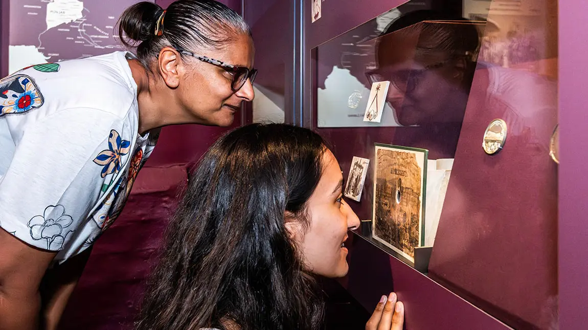 Two people bending down to look at a museum display about Duleep Singh