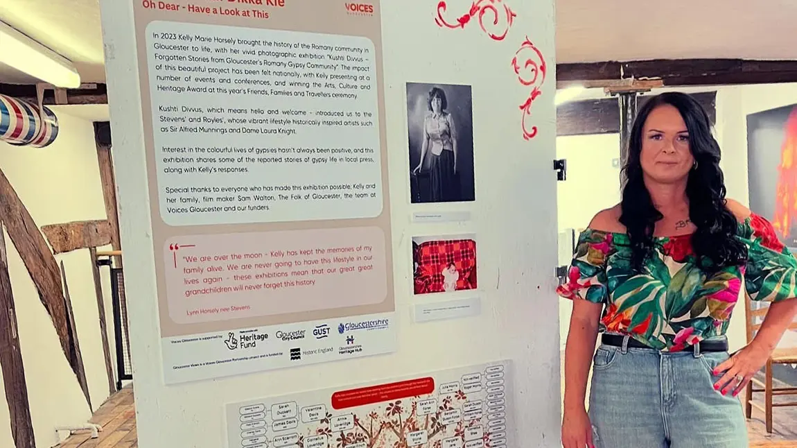A community grant recipient stands next to an interpretation board with exhibition information