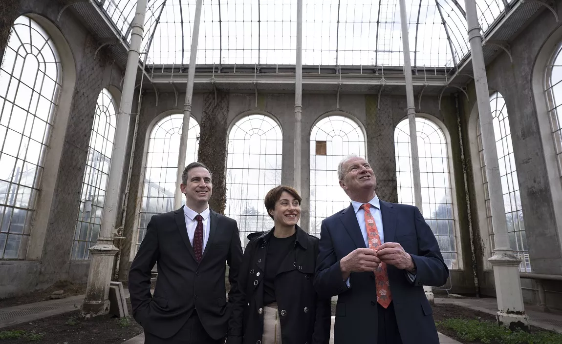 Three people standing and talking in a Victorian plant conservatory 