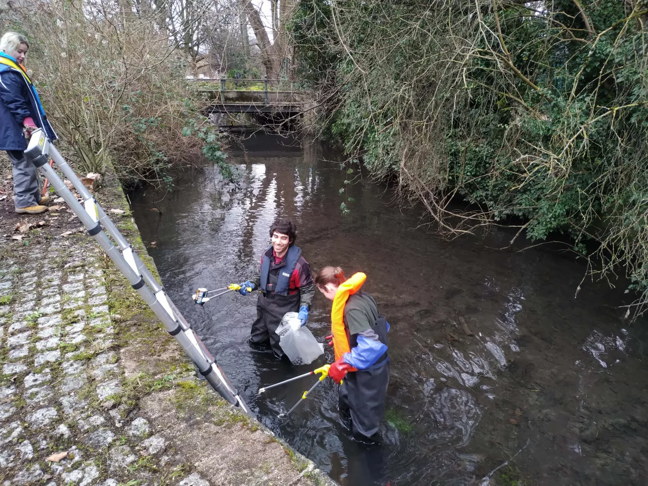 People finding litter in a stream