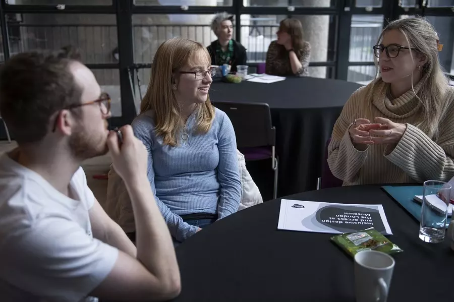 Three people sitting and discussing at a table in a conference room