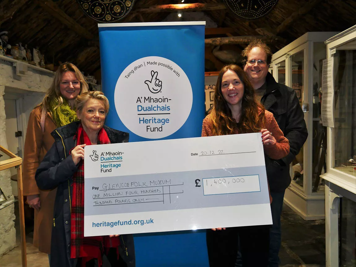 People standing inside a museum holding a giant check 