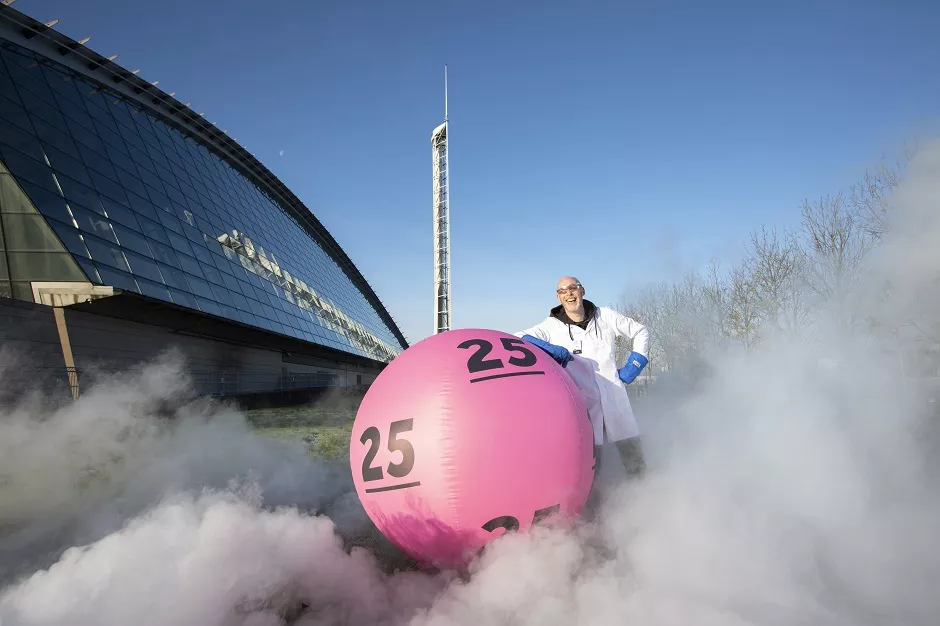 Science Centre Glasgow - National Lottery.jpg MAn stands in front of Science Centre with a large Lottery ball showing number 25