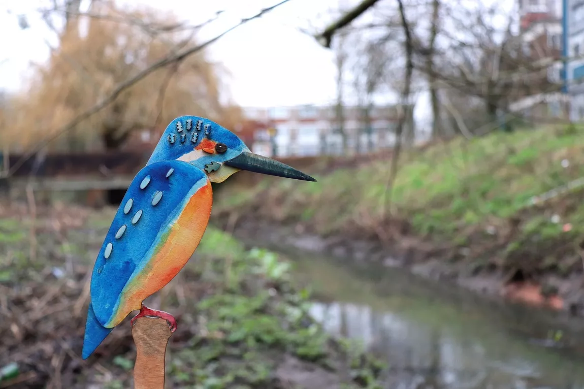 A small sculpture of a kingfisher on a wooden post next to a Coventry waterway