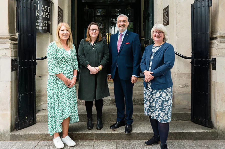 Four people stand outside a building and smile at camera