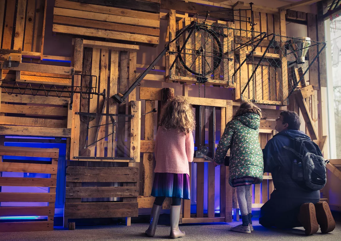 An adult and two children interact with one of the exhibits at Reimagining Reality