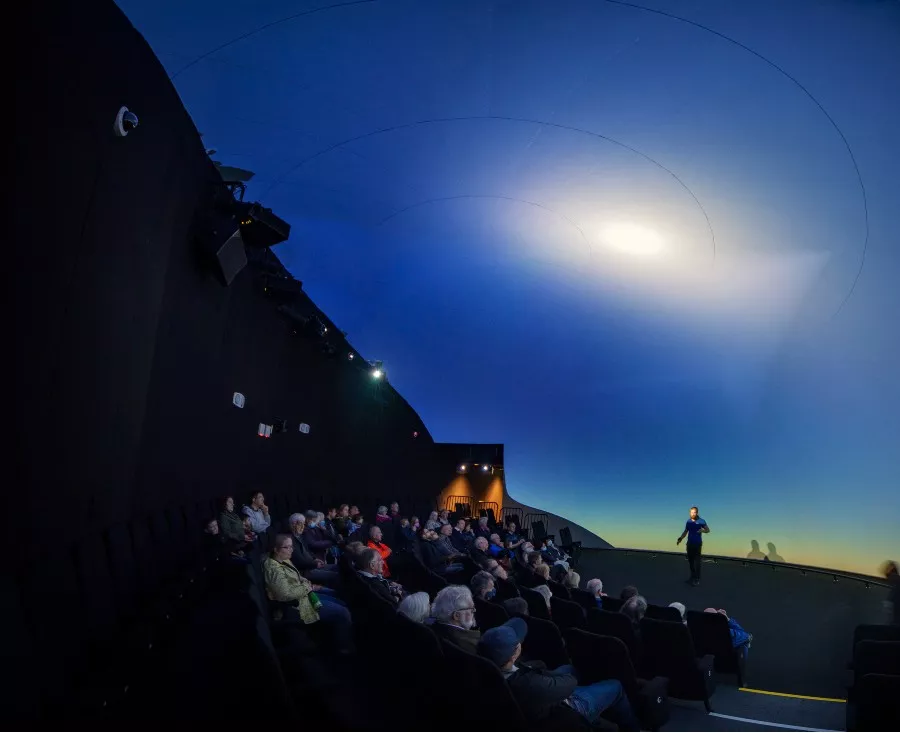 Audience sit facing person on stage