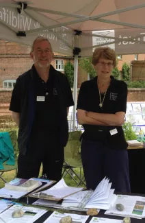 Two people standing in a marquee with stones and information leaflets