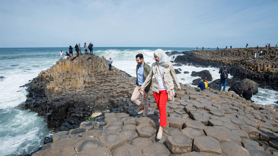 People walk across the iconic landscape of the Giant's Causeway coastal route