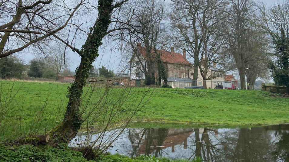 Photograph of a building and its reflection in a pond.